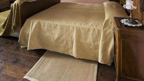 Un dormitorio con una cama grande, vigas de madera en el techo, un armario de madera, una mesita de noche con una lámpara y un cuadro enmarcado en la pared.