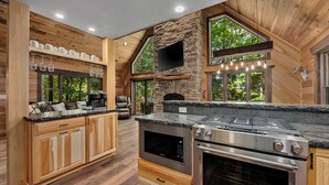 Una cocina moderna con armarios de madera, estufa integrada y una pared decorativa de piedra.