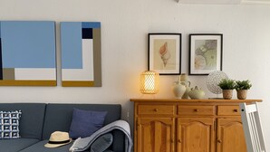 A living room with a grey sofa, wooden cabinet, and wall art. - Les Doyes 116 (Peníscola)