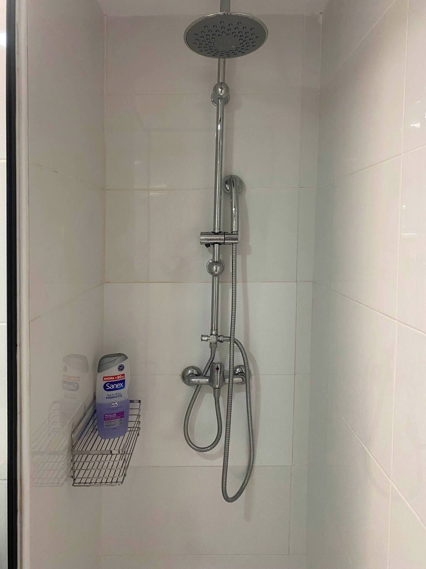 A shower with a handheld showerhead and a wall-mounted faucet.