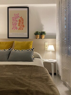 Relax in a serene bedroom with a large bed, framed artwork, and potted plants.