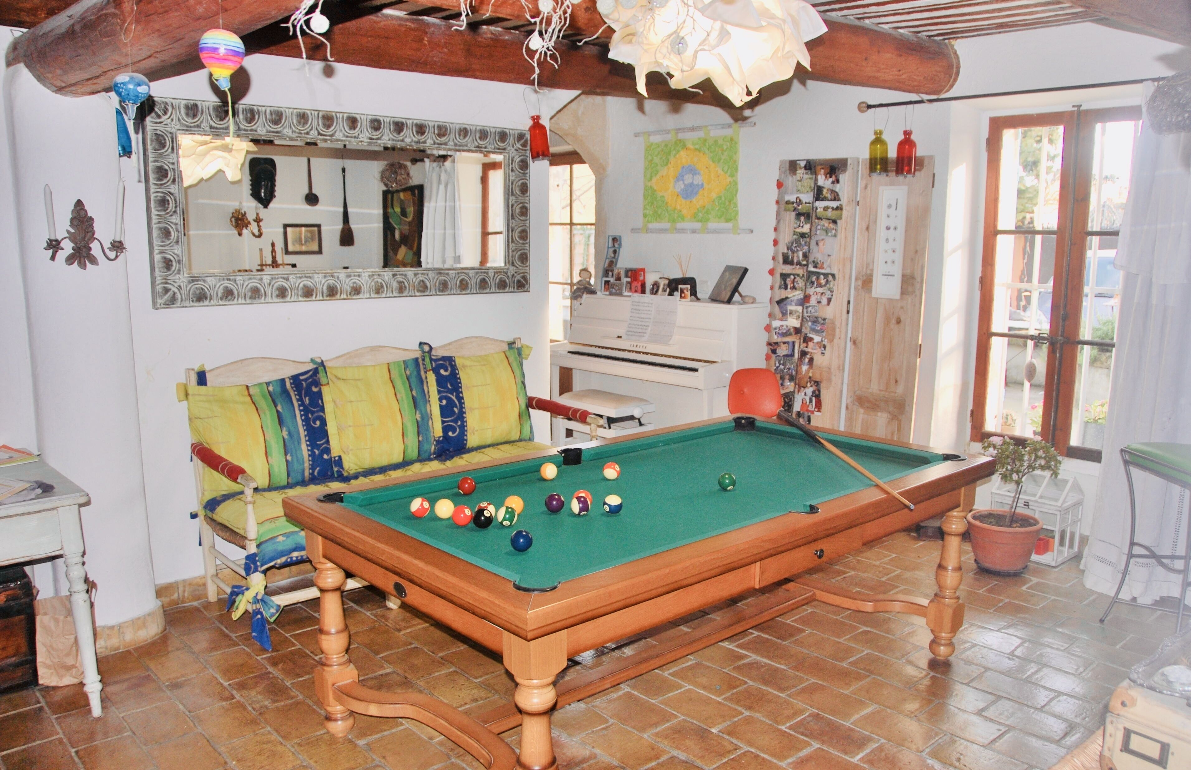 Une table de billard dans une pièce où se trouvent un canapé, un piano et divers éléments de décoration.