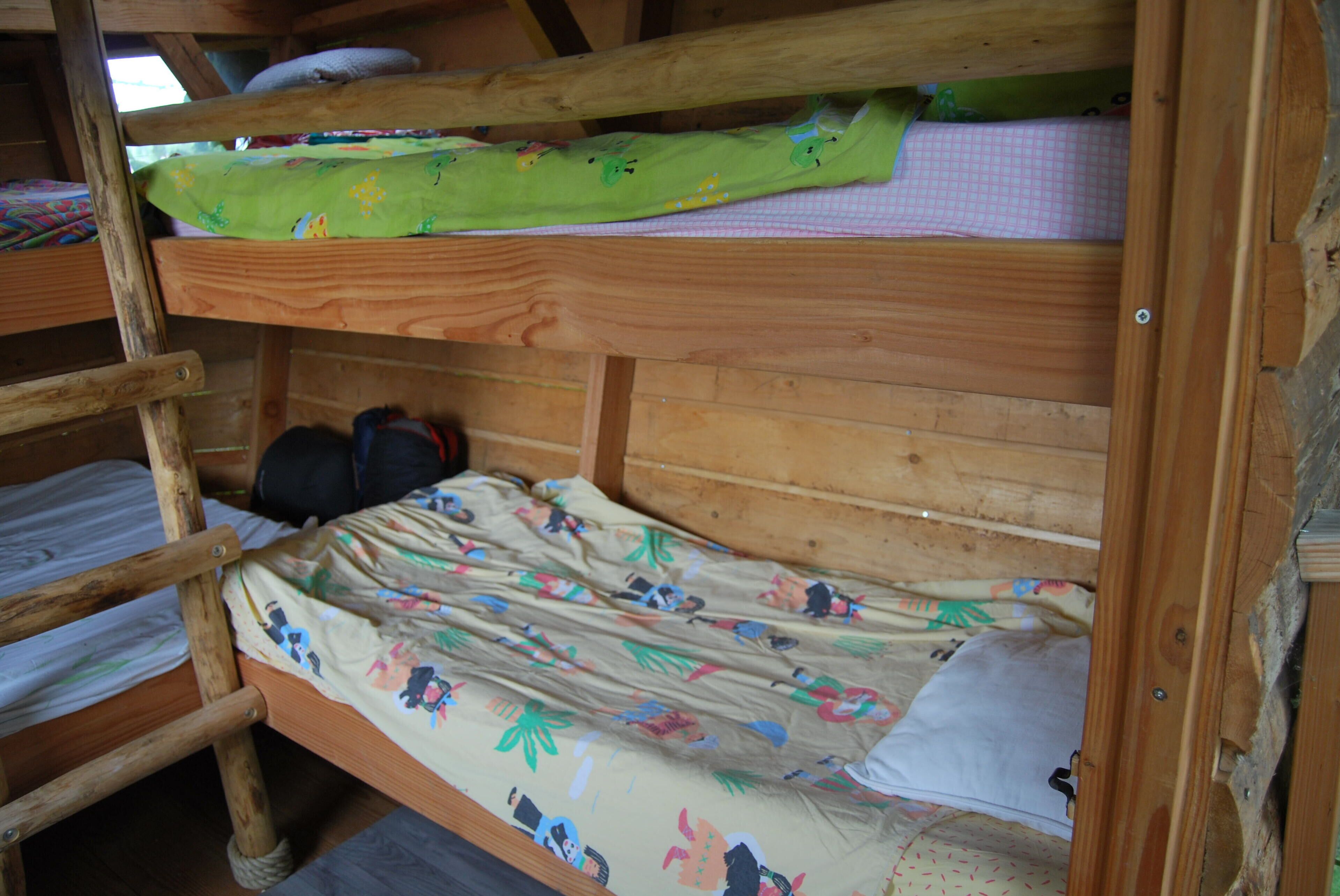 A bunk bed with a green blanket and a floral bedspread.