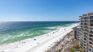Ein Hotel direkt am Strand mit mehreren Etagen, einem Sandstrand und einem Pier im Hintergrund.
