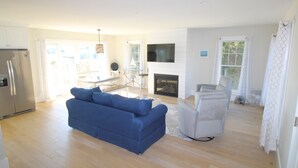 Un salon spacieux avec un canapé bleu, un fauteuil blanc et une cheminée.