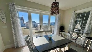 Un espace repas comprenant une table et des chaises, un luminaire suspendu et une vue sur l’extérieur.