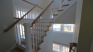 Un escalier à plusieurs niveaux, doté de rampes blanches et de marches en bois, menant à l’étage supérieur.