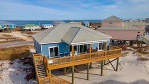 Een strandhuis met een houten terras en een trap naar de ingang.