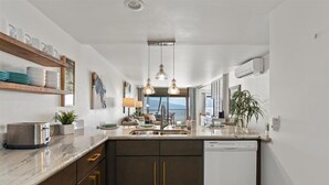 Een moderne keuken met een marmeren aanrechtblad, inbouwkeukens en een vaatwasser.