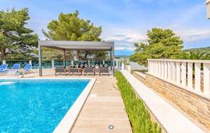 A pool area with lounge chairs and a covered seating area.
