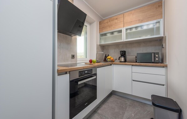 A modern kitchen with white cabinets, a black oven, a microwave, and a coffee maker.