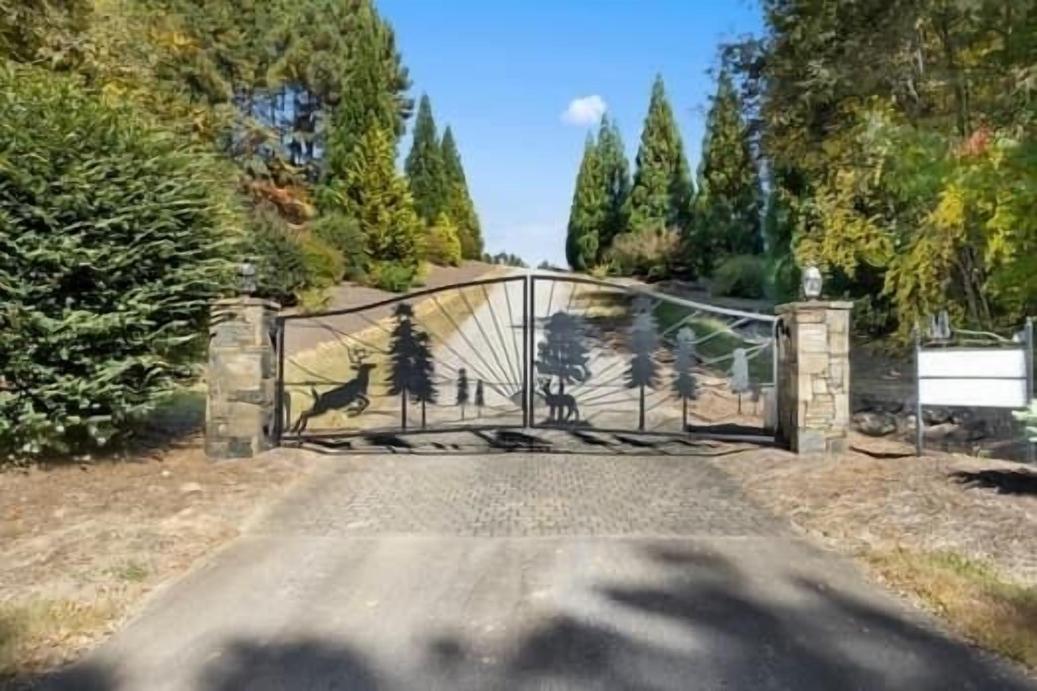 A gated entrance with a deer and tree silhouette mural.