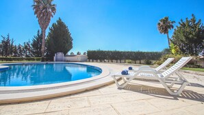 Une piscine avec des chaises longues et des palmiers.