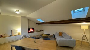 A spacious loft with a wooden dining table, blue chairs, a gray sofa, and a TV displaying a fireplace. - LYON PRESQU ILE musée des tissus - Air-conditioned APARTMENT ideal for visiting LYON (Lyon)