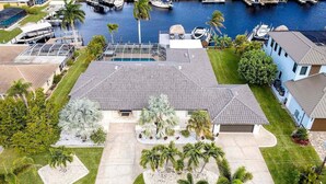 A residential area with a house featuring a large driveway, a swimming pool, and a marina with boats.