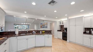 A spacious kitchen with white cabinetry, a central island, and a large window providing natural light.