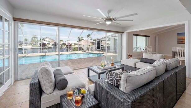 A spacious balcony with a pool, wicker furniture, and a ceiling fan.