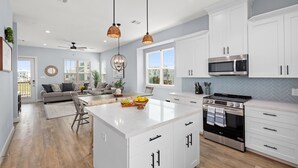 A spacious kitchen with white cabinetry, a large island, and modern appliances including a microwave and oven.
