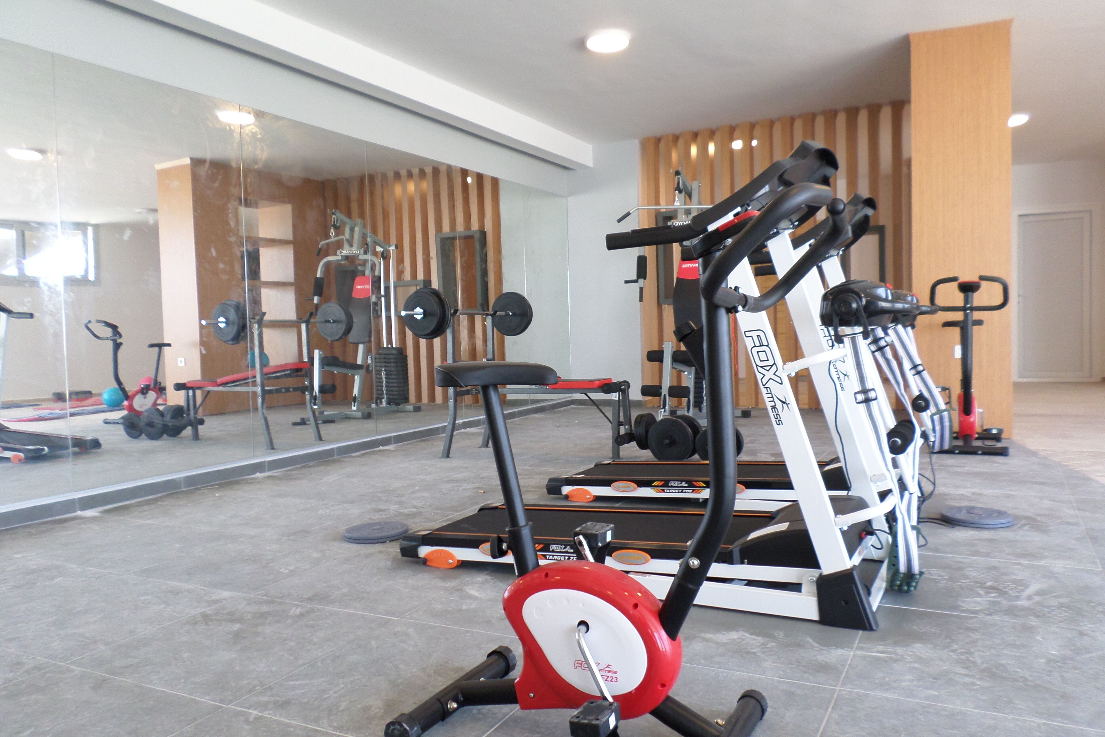 A gym with exercise equipment, a mirrored wall, and a wooden panel wall.