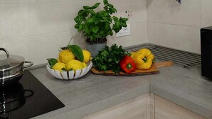 Una cocina con un armario blanco, una pequeña planta en maceta y una variedad de productos frescos en la encimera.