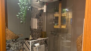 A compact bathroom with a white sink, toilet, and glass-enclosed shower. - Studio Cosy et Tout Confort à Proximité Immédiate du Canal ! Cœur de Paris (Paris)