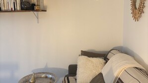 A living room with a sofa, a coffee table, and a bookshelf. - Studio Cosy et Tout Confort à Proximité Immédiate du Canal ! Cœur de Paris (Paris)