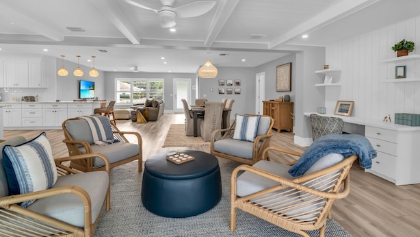 A spacious living area with wicker furniture, a round ottoman, and a ceiling fan. - Luxury Golf-View Oasis with Heated Pool & Quiet Marco Island Location (Marco Island)