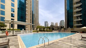 A swimming pool with a tiled deck, surrounded by high-rise buildings. - Maison Privee - Modern Beach Living in the Heart of Dubai Marina (Dubai)
