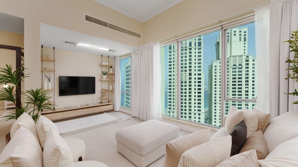 A modern living room with a large flat-screen TV, comfortable seating, a large window with a city view, and a minimalist decor. - Maison Privee - Modern Beach Living in the Heart of Dubai Marina (Dubai)