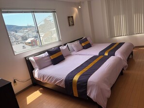 Ein Doppelbett mit Kopfteil, ein Nachttisch und ein Fenster mit Blick auf Gebäude.