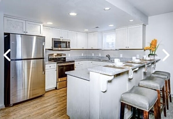 A modern kitchen with white cabinets, stainless steel appliances, and a central island with bar stools.
