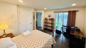 A bedroom with a bed, a desk, and a chair. There is a door leading to another room and a window with curtains. - 2 bedroom w/ expansive water views (Phippsburg)