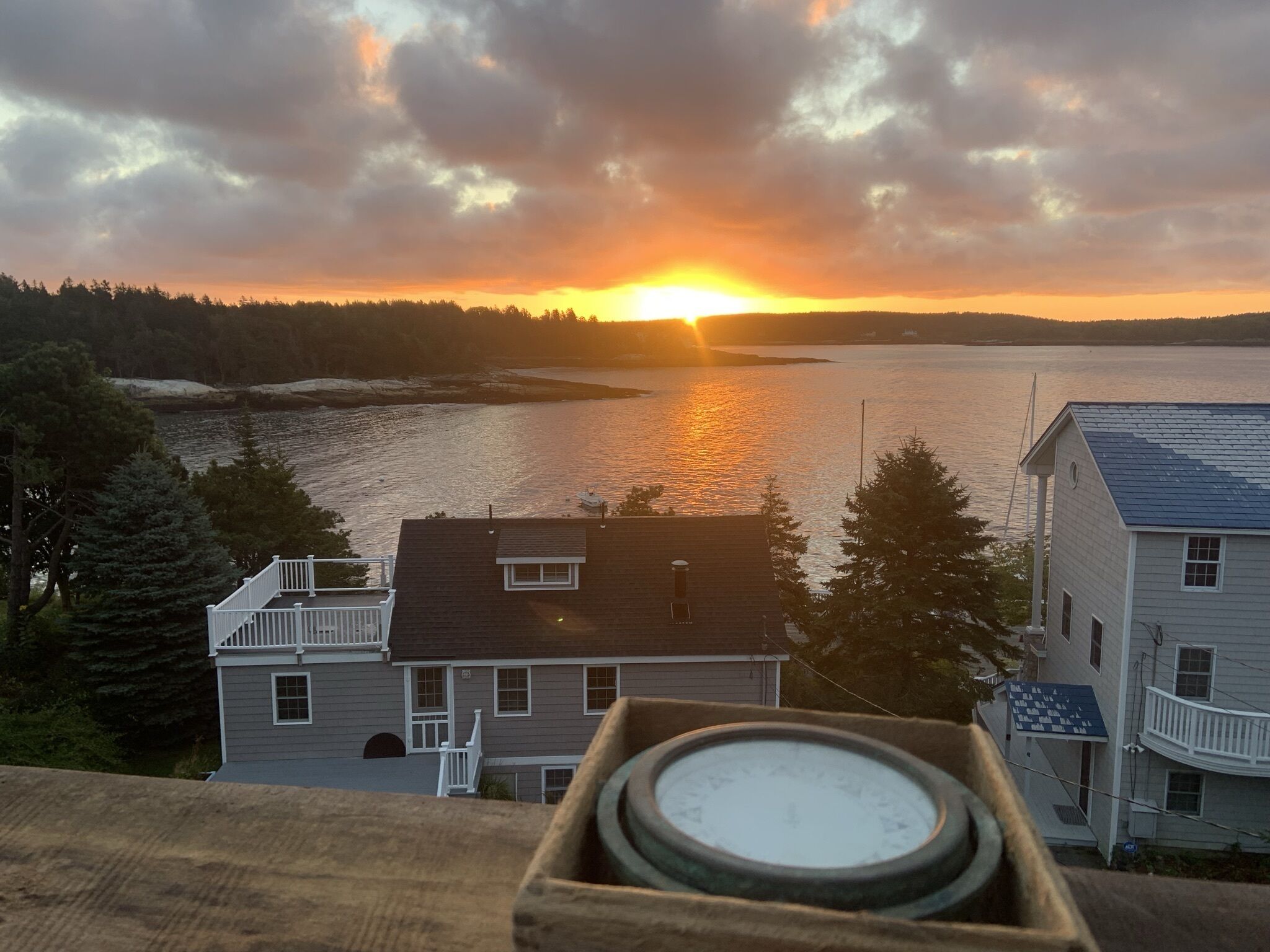 A residential area with houses overlooking a body of water during sunset.