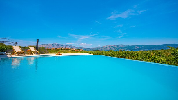 Une piscine avec deux chaises longues et une vue sur les montagnes en arrière-plan.