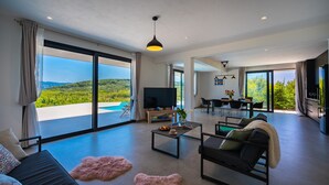 Un vaste espace de vie doté d’une grande porte-fenêtre coulissante donnant sur un balcon avec piscine, d’un téléviseur à écran plat, d’un coin repas et d’un canapé agrémenté d’un tapis moelleux.