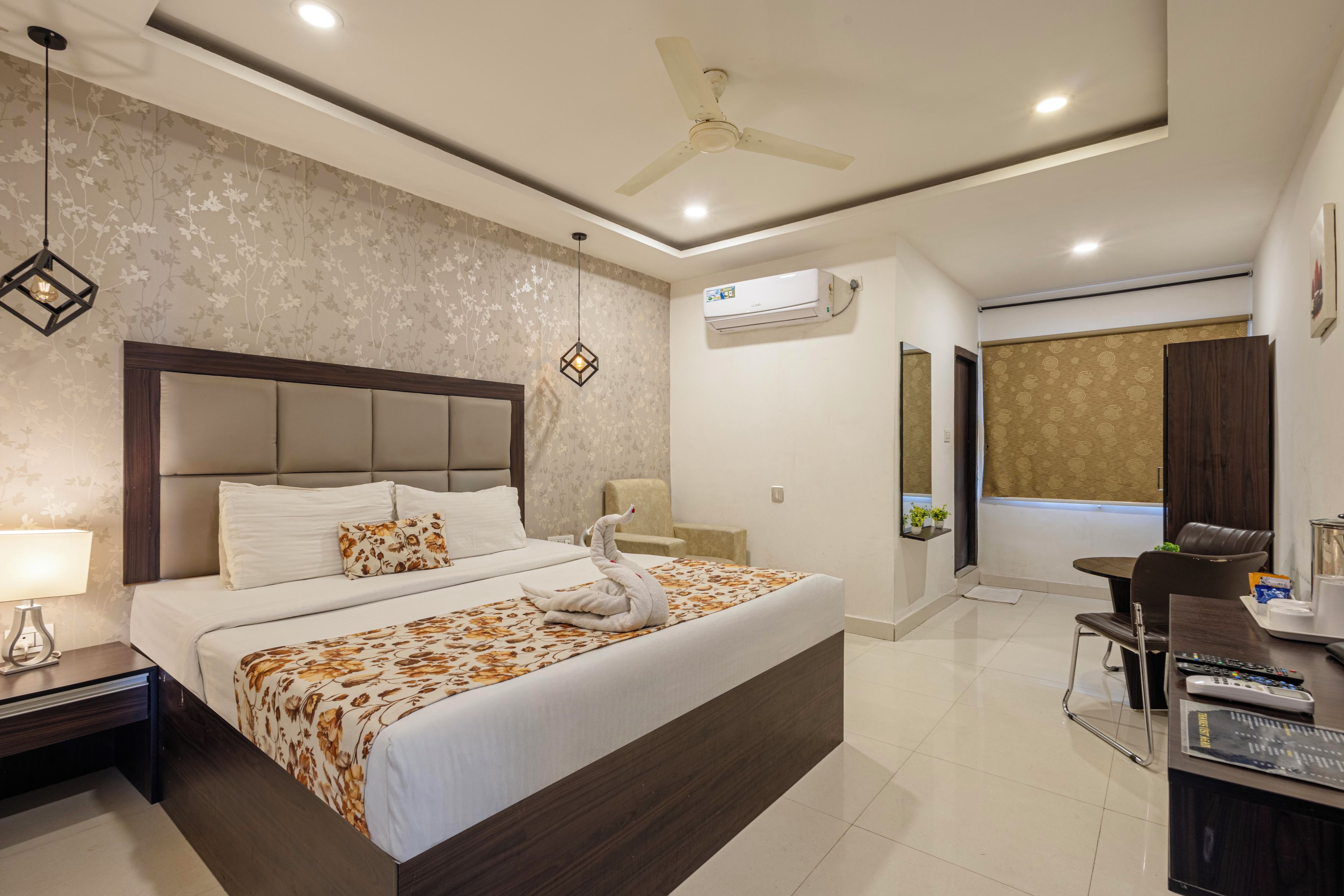 Une chambre d’hôtel moderne dotée d’un grand lit, d’un bureau avec une chaise, d’un ventilateur de plafond et d’un appareil de climatisation.