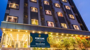 A multi-story hotel with illuminated windows and a signboard for Fortune Hotels & Resorts.