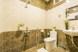 Baño con inodoro, lavabo, ducha y dos macetas.