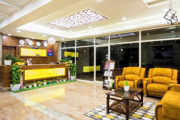 Un vestíbulo de hotel con mostrador de recepción, zona de estar y puerta de entrada de vidrio.