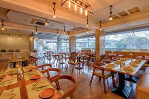 A restaurant with multiple tables set for dining, featuring wooden chairs and a modern interior design. - Hotel Fortune Hyderabad Airport Zone (Hyderabad)