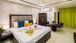 A hotel room with a bed, bedside table, desk, chair, and a ceiling fan.