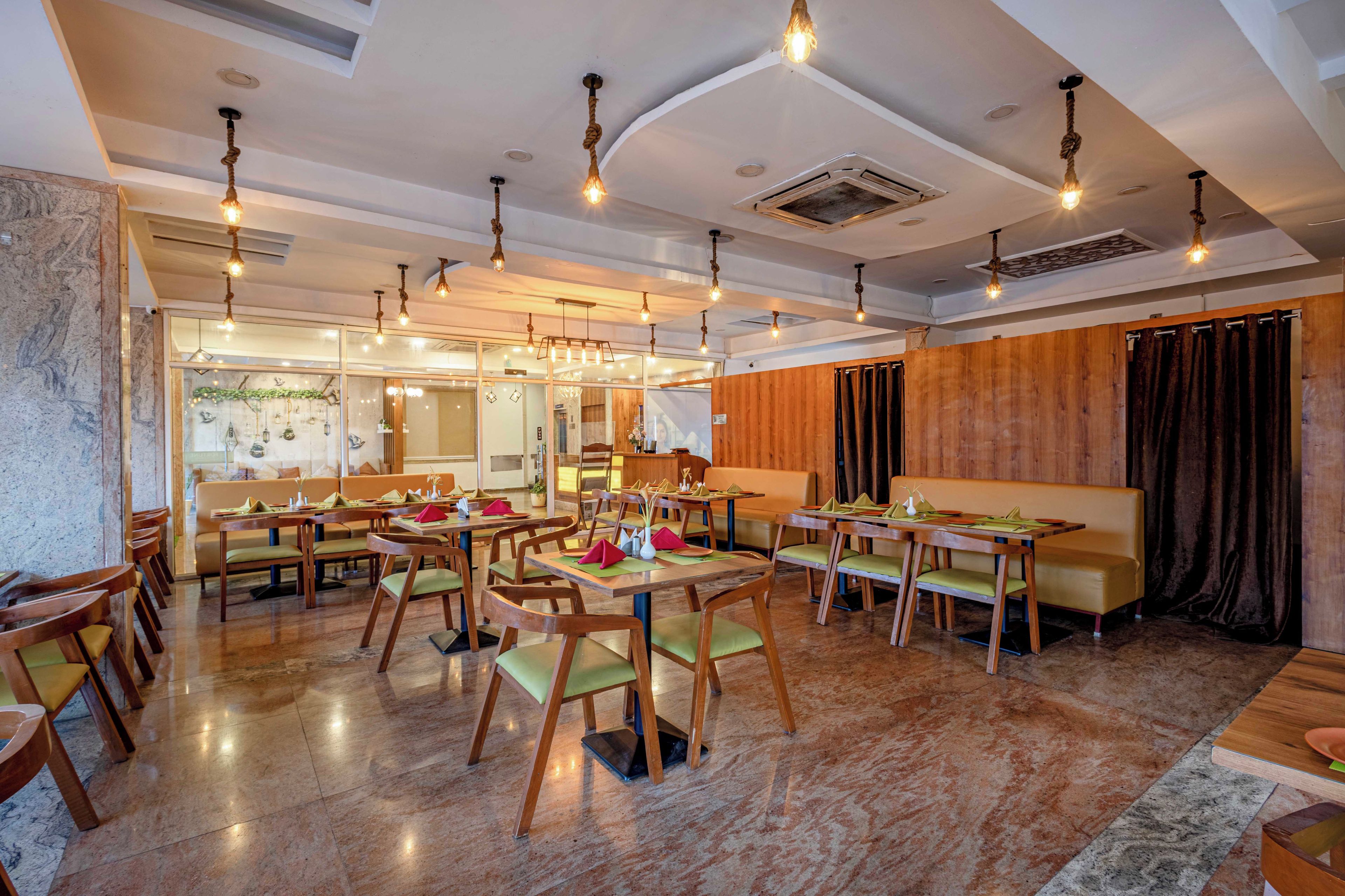 A modern restaurant with wooden furniture, marble flooring, and pendant lighting.