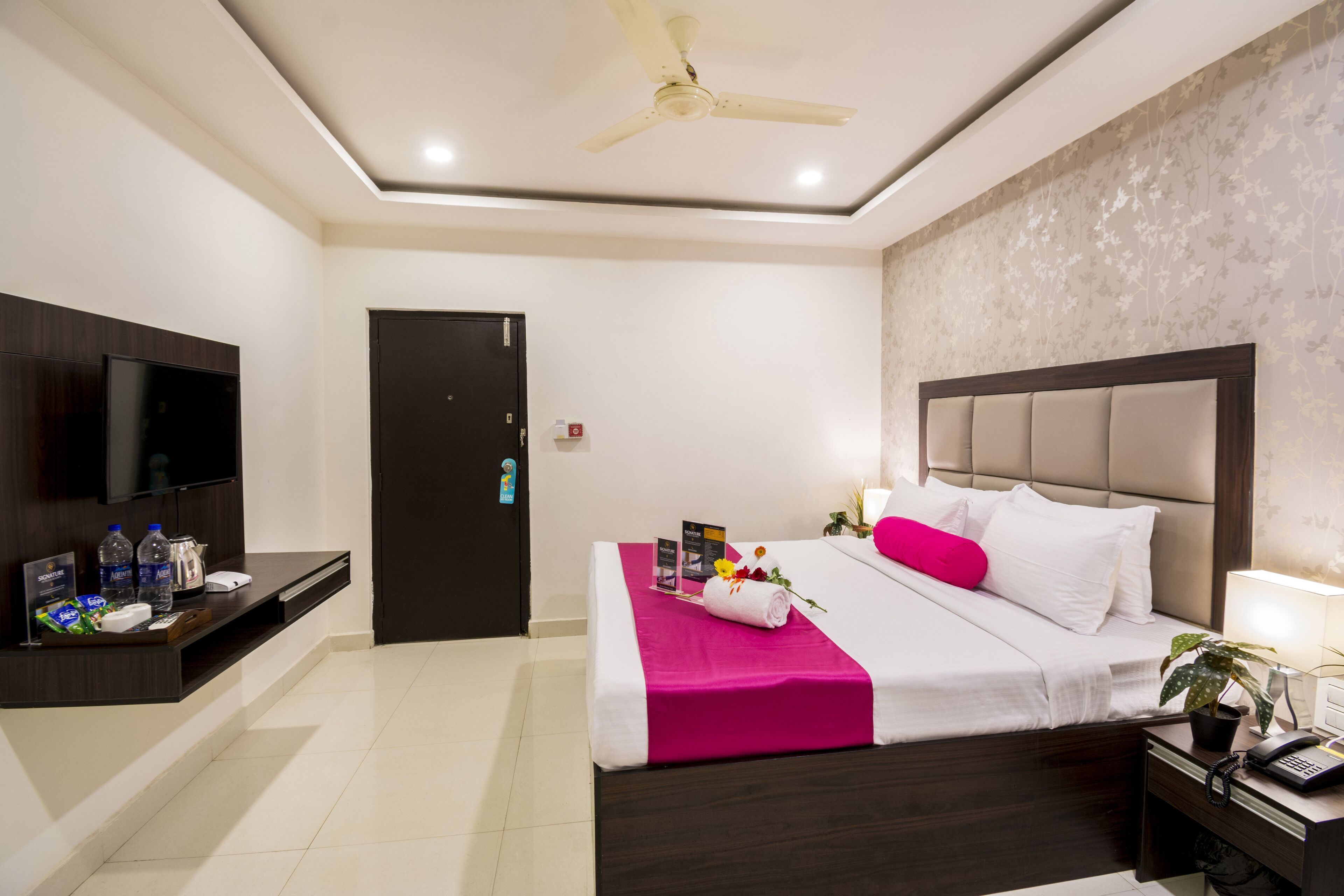 Una habitación de hotel moderna con una cama, un televisor, un escritorio con teléfono y un ventilador de techo.