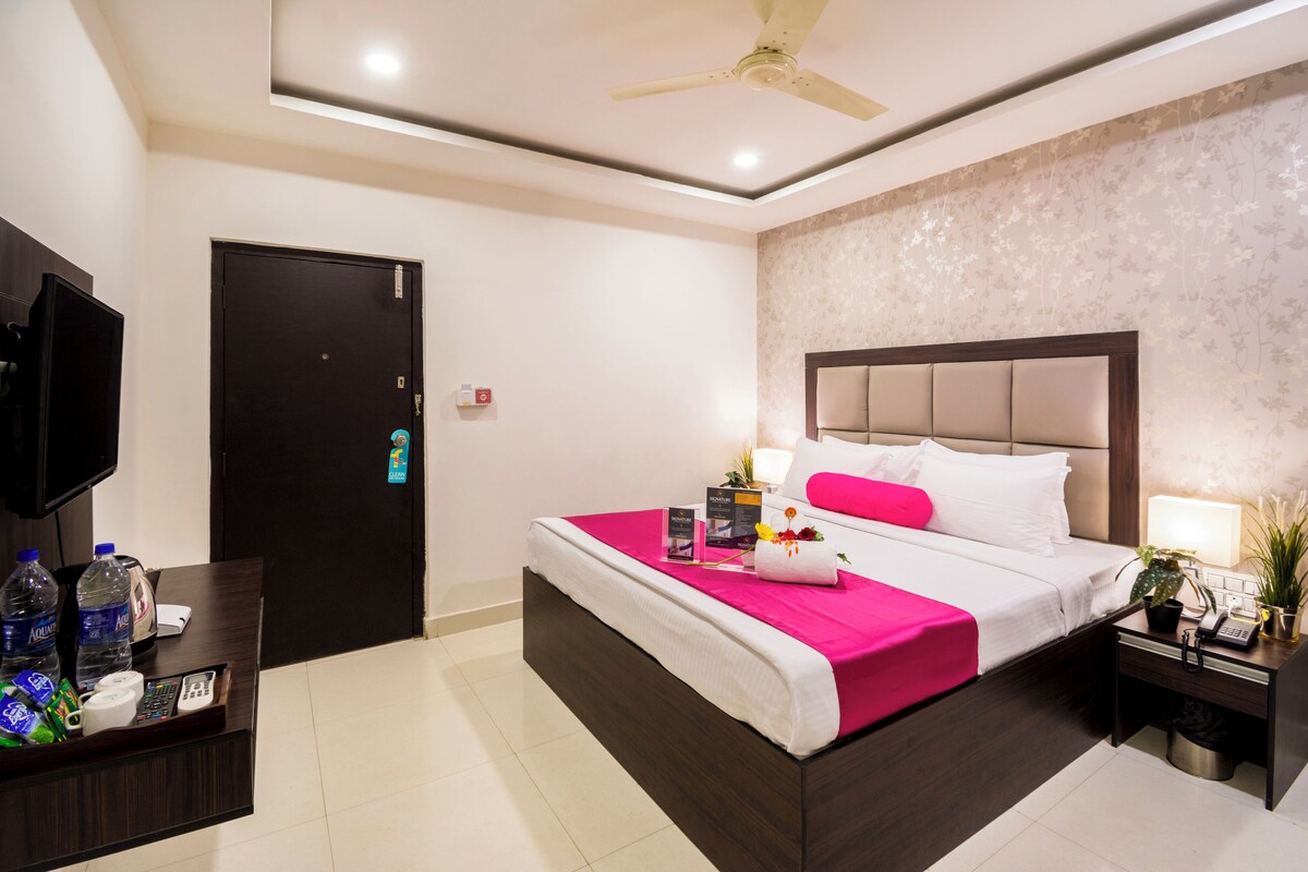 A hotel room with a bed, bedside table, nightstand, and a television on a stand.