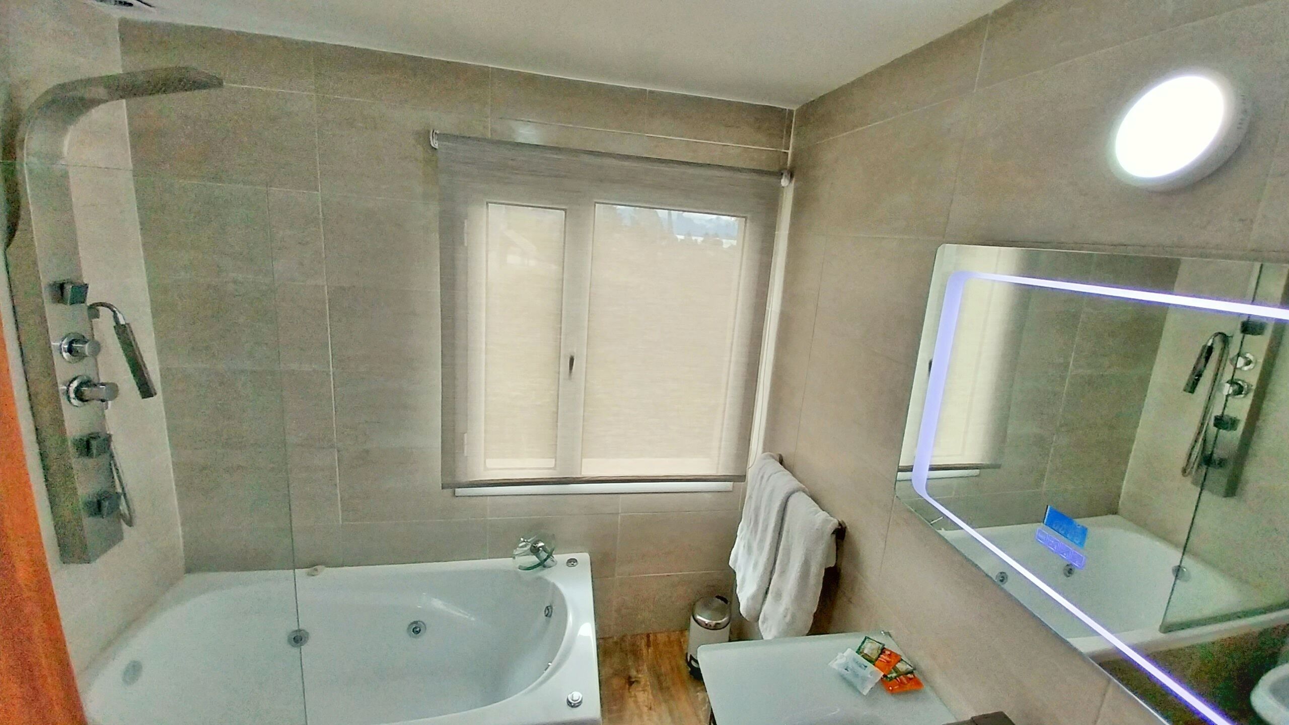 A bathroom with a bathtub, a sink, a mirror, and a window.