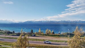 A coastal road with a lake and mountains in the background. - Las Victorias Suites Bariloche (San Carlos de Bariloche)
