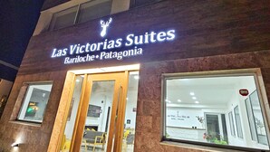Un hotel llamado "Las Victorias Suites", con entrada visible y un cartel que indica la ubicación en Bariloche, Patagonia.