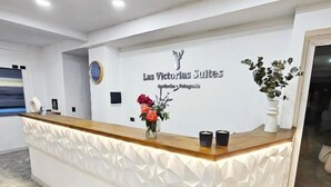 Una recepción con diseño blanco y de madera, un logotipo y un arreglo floral.
