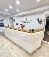 A reception desk with a white and wooden design, a logo, and a floral arrangement.