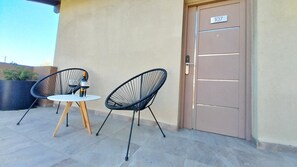An outdoor seating area with two chairs and a small table, a door with the number 107, and a potted plant in the background. - Las Victorias Suites Bariloche (San Carlos de Bariloche)